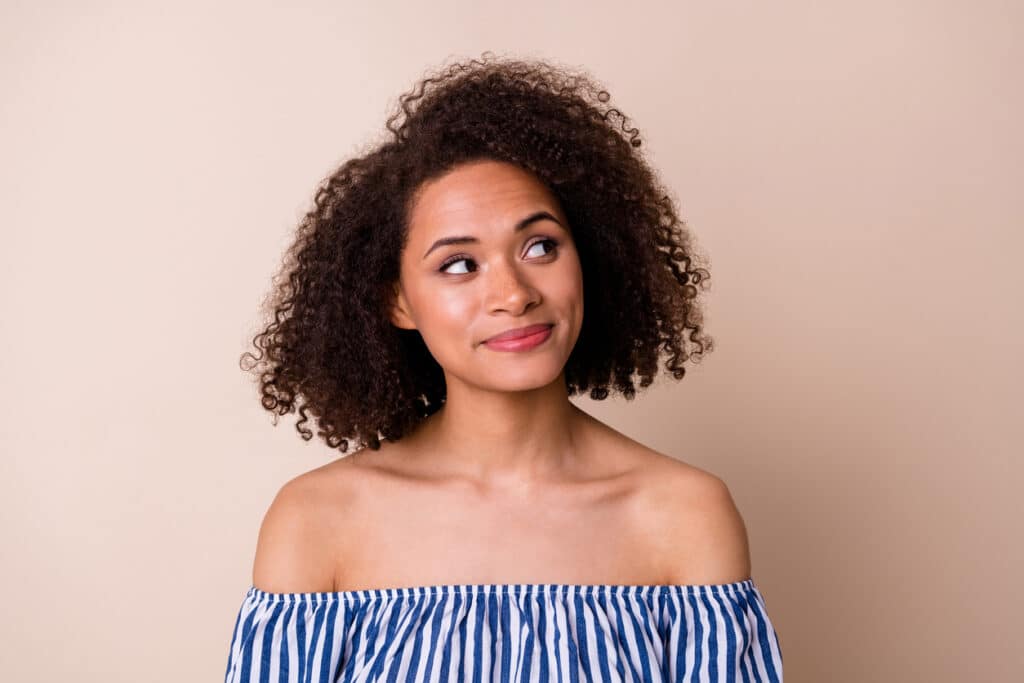 Woman of Color pondering whether to go with the scalp micropigmentation treatment.